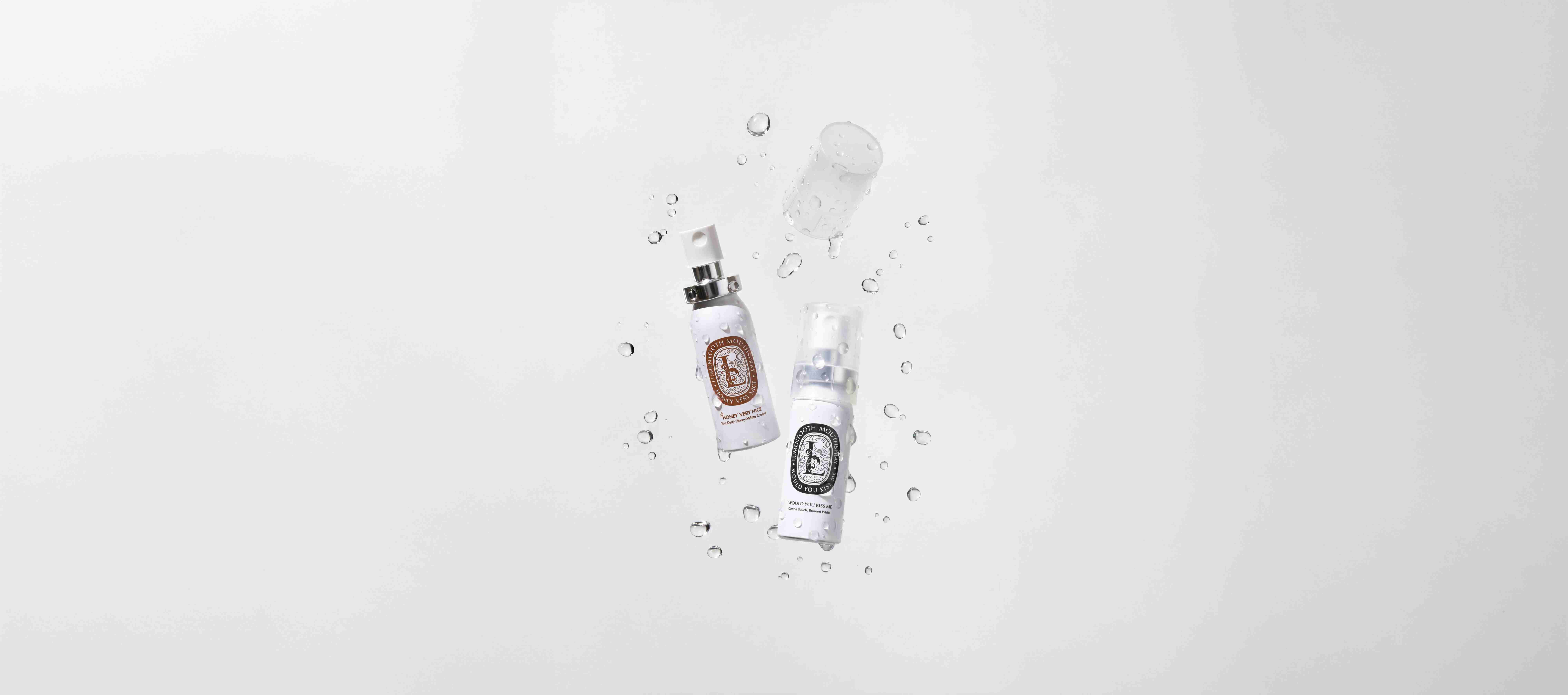 Two Lumentooth Mouthspray bottles floating among water droplets