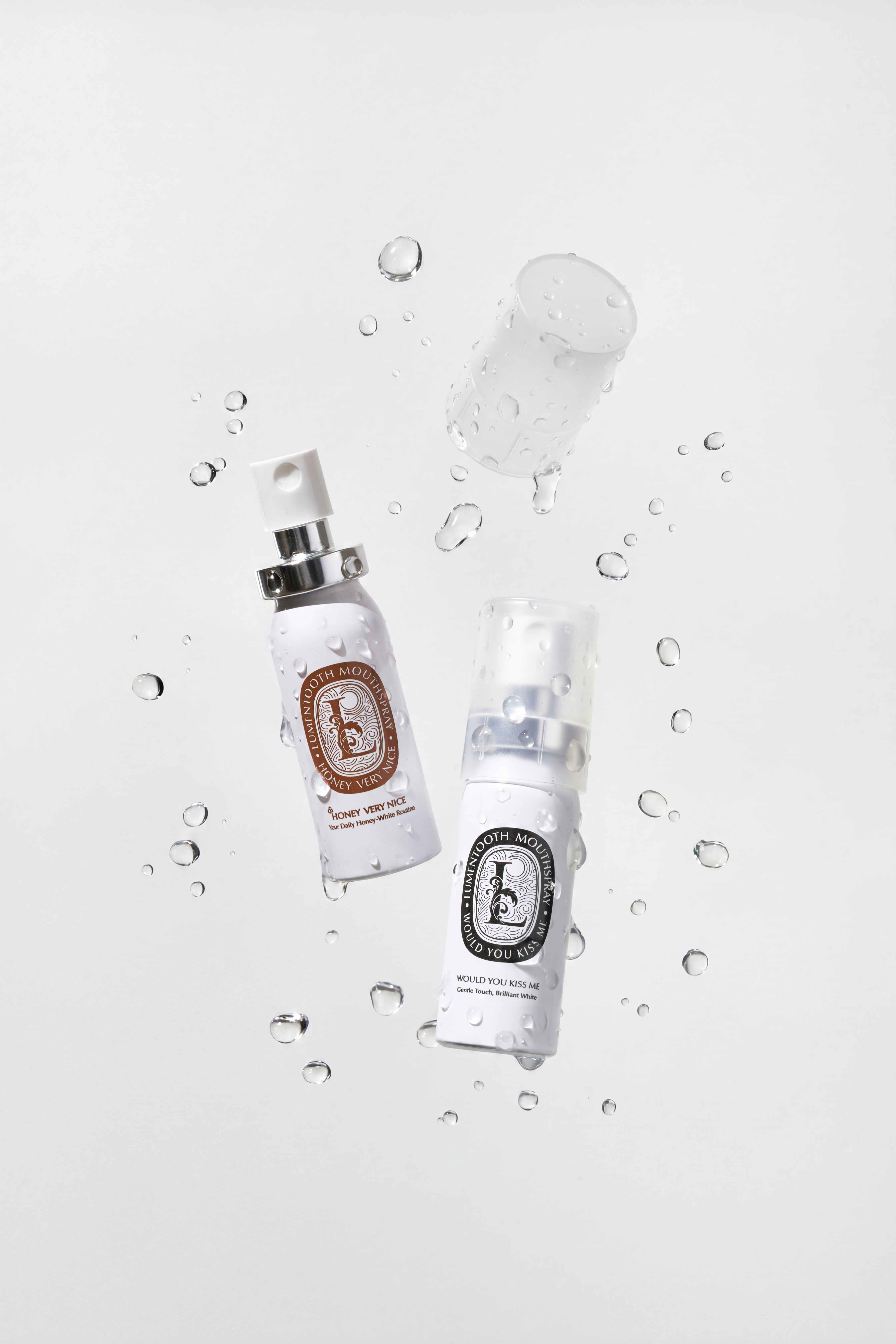 Two Lumentooth Mouthspray bottles floating among water droplets